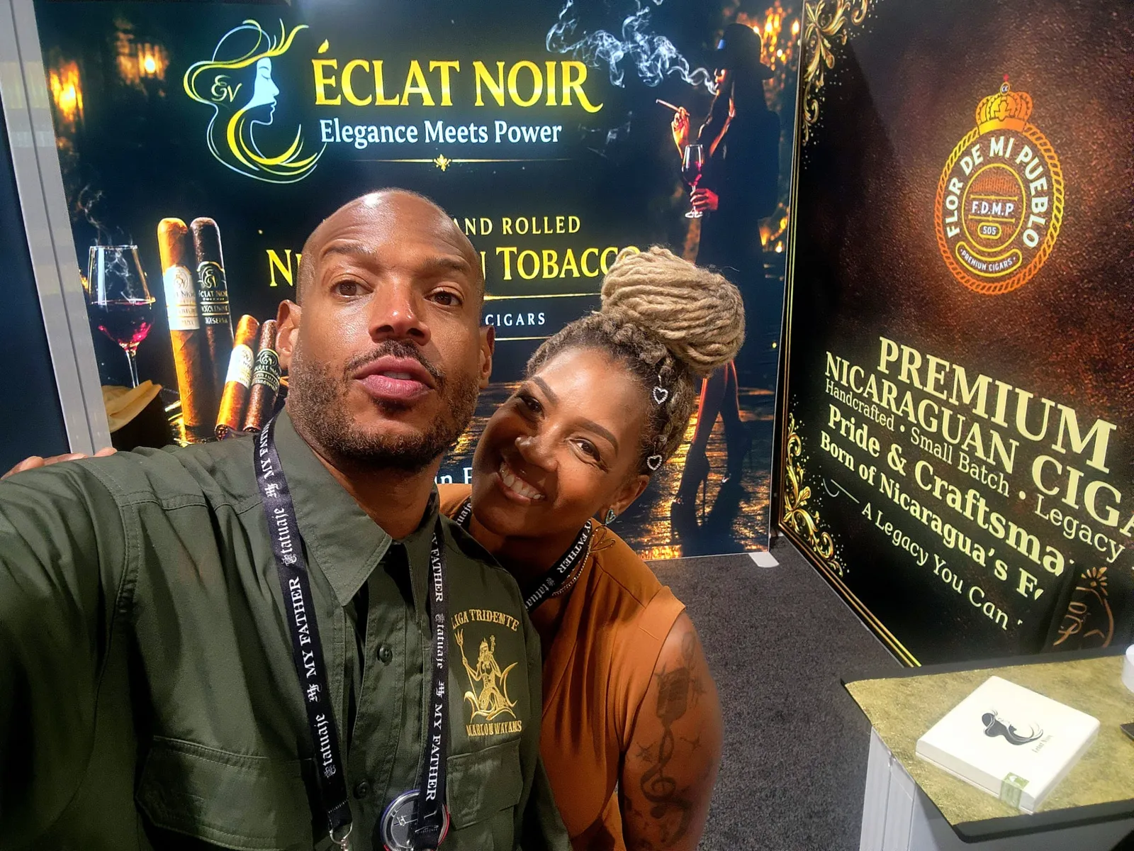 Close portrait of Founder and CEO L. Howard with an attendee in front of the ÉCLAT NOIR booth signage, PCA Trade Show, New Orleans, April 2026.