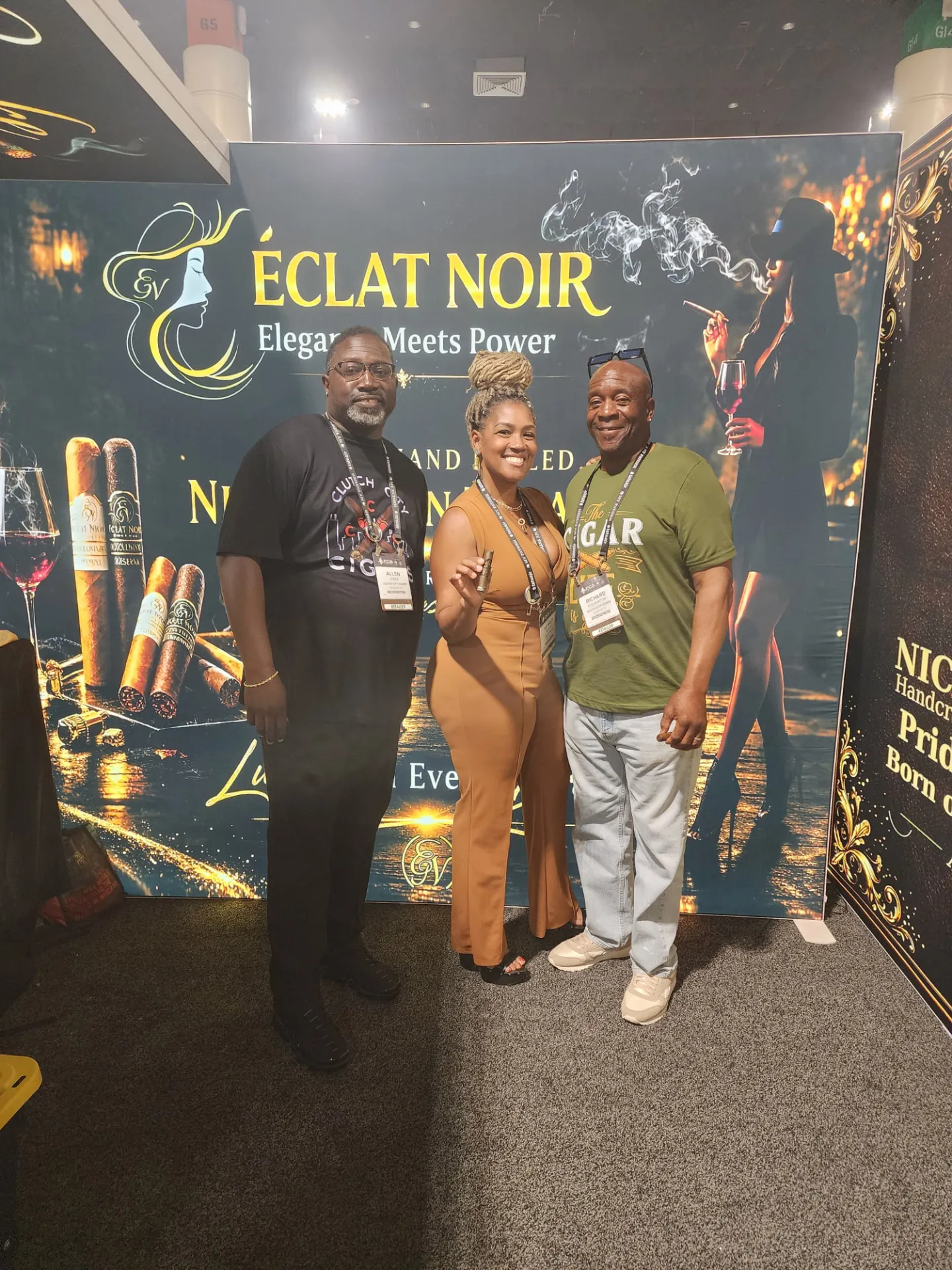 Founder and CEO L. Howard holding a cigar between two attendees at the ÉCLAT NOIR booth, PCA Trade Show, New Orleans, April 2026.