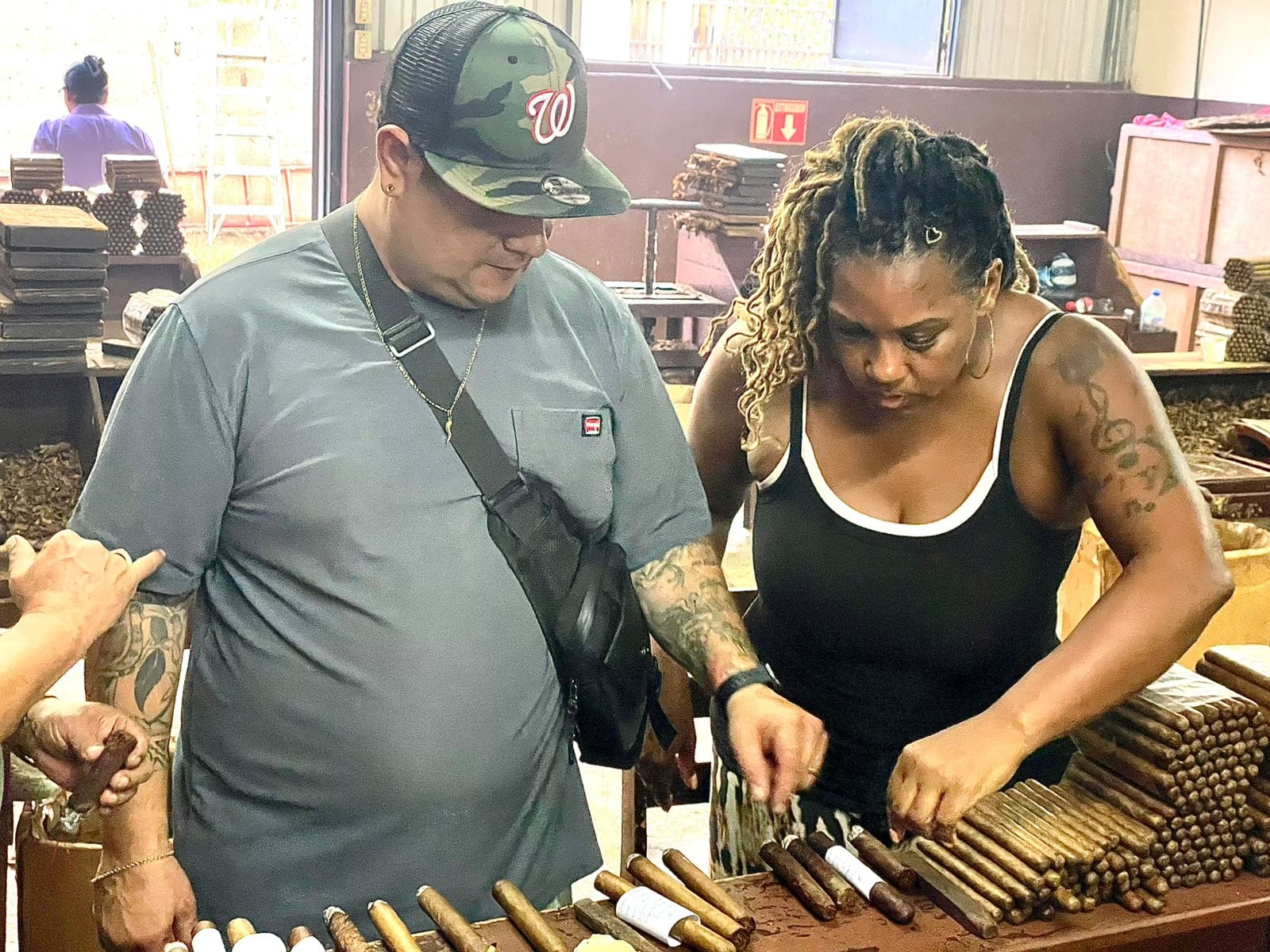 Founder L. Howard inspecting rows of freshly rolled cigars at the bench alongside the production team in Estelí.