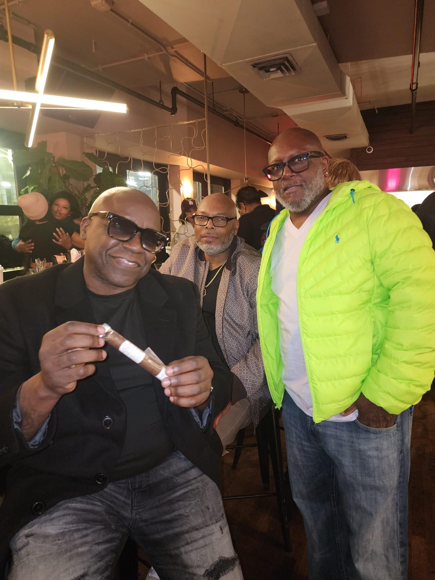 Three guests gathered at an ÉCLAT NOIR event, one holding a banded cigar.