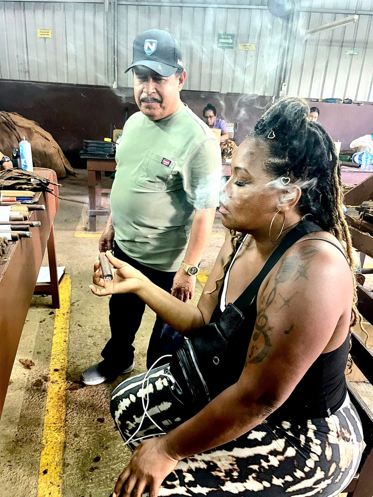 Founder L. Howard drawing on a cigar at the Estelí factory bench while a master roller looks on.
